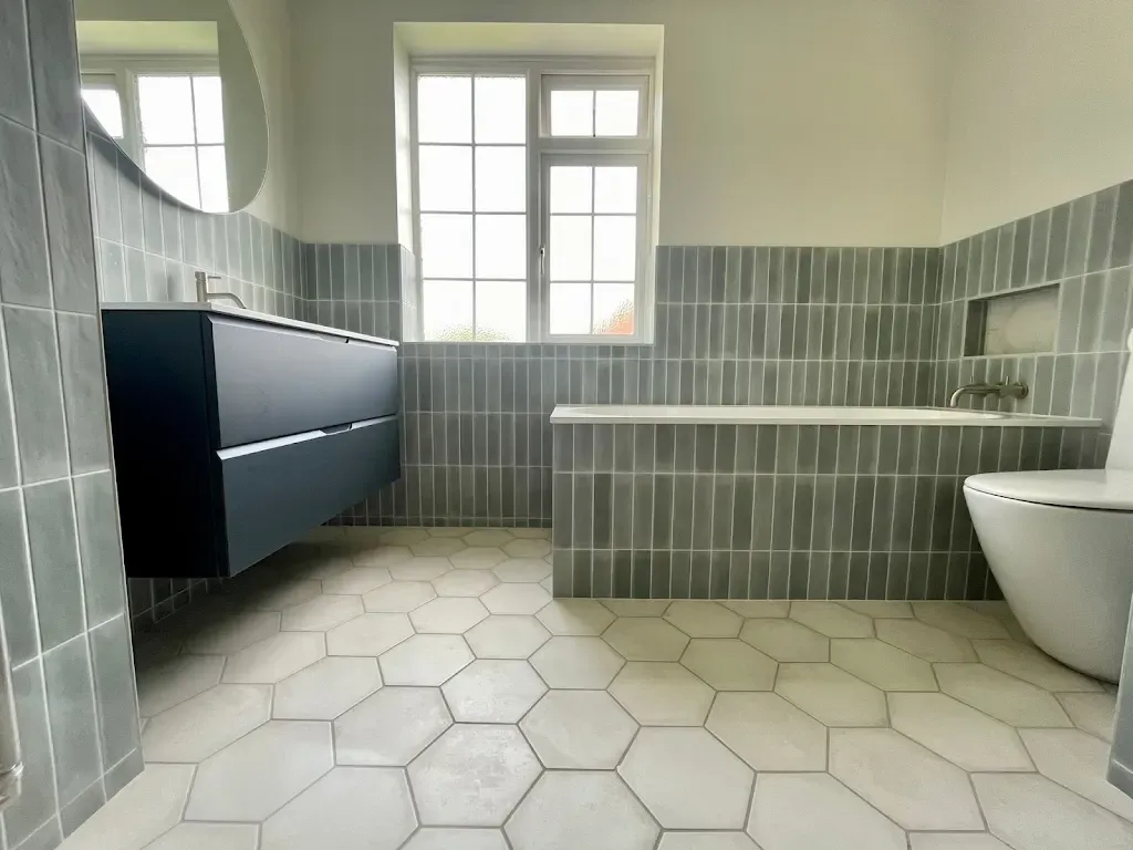 A fully tiled bathroom by Prestige Tiling: grey wall tiles, hexagon floor, freestanding bath and vanity unit